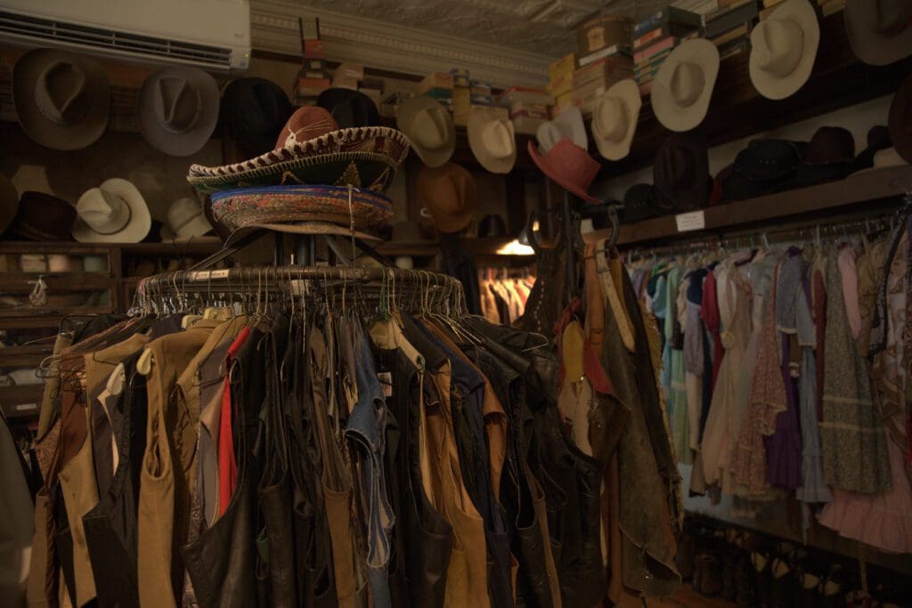 View of cowbow hats, vests and clothing on racks for costume rentals