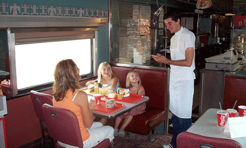Waiter taking an order at 50s style train diner in 1880 Town
